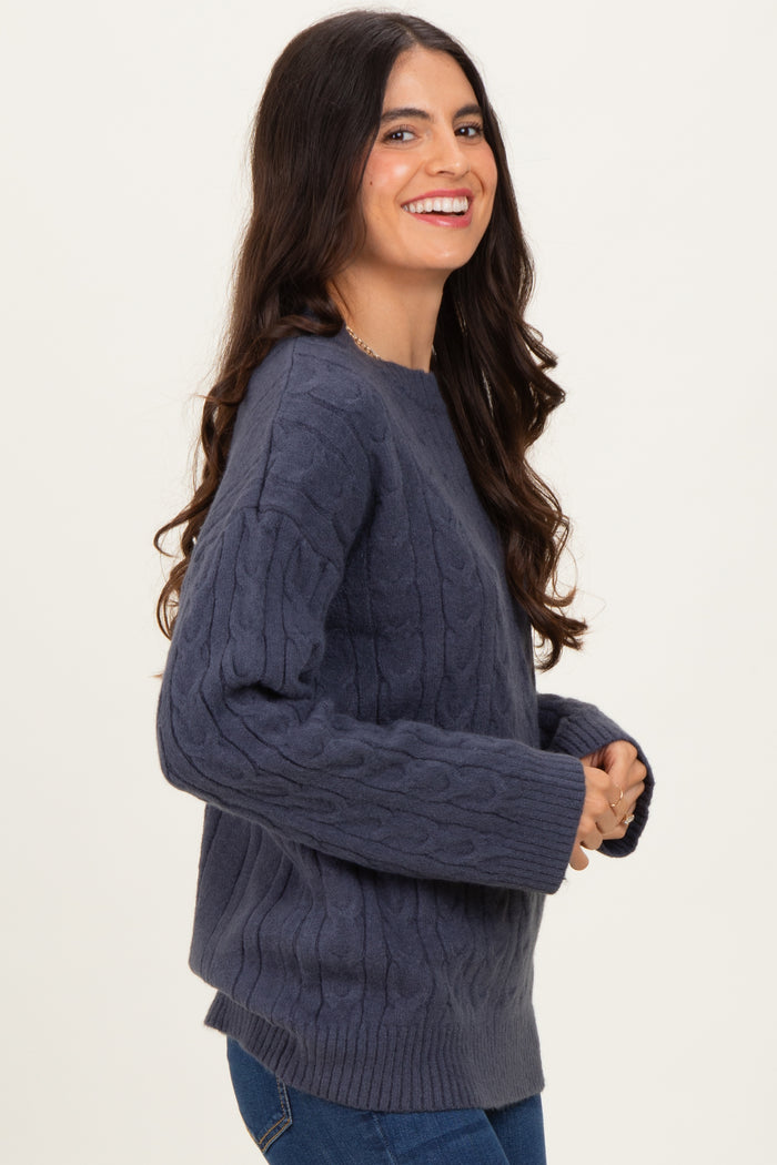 woman wearing a dark grey cable knit sweater with a relaxed fit and long sleeves, smiling at the camera