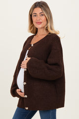 woman wearing a dark brown chunky knit maternity cardigan with oversized sleeves and buttons, showing her baby bump