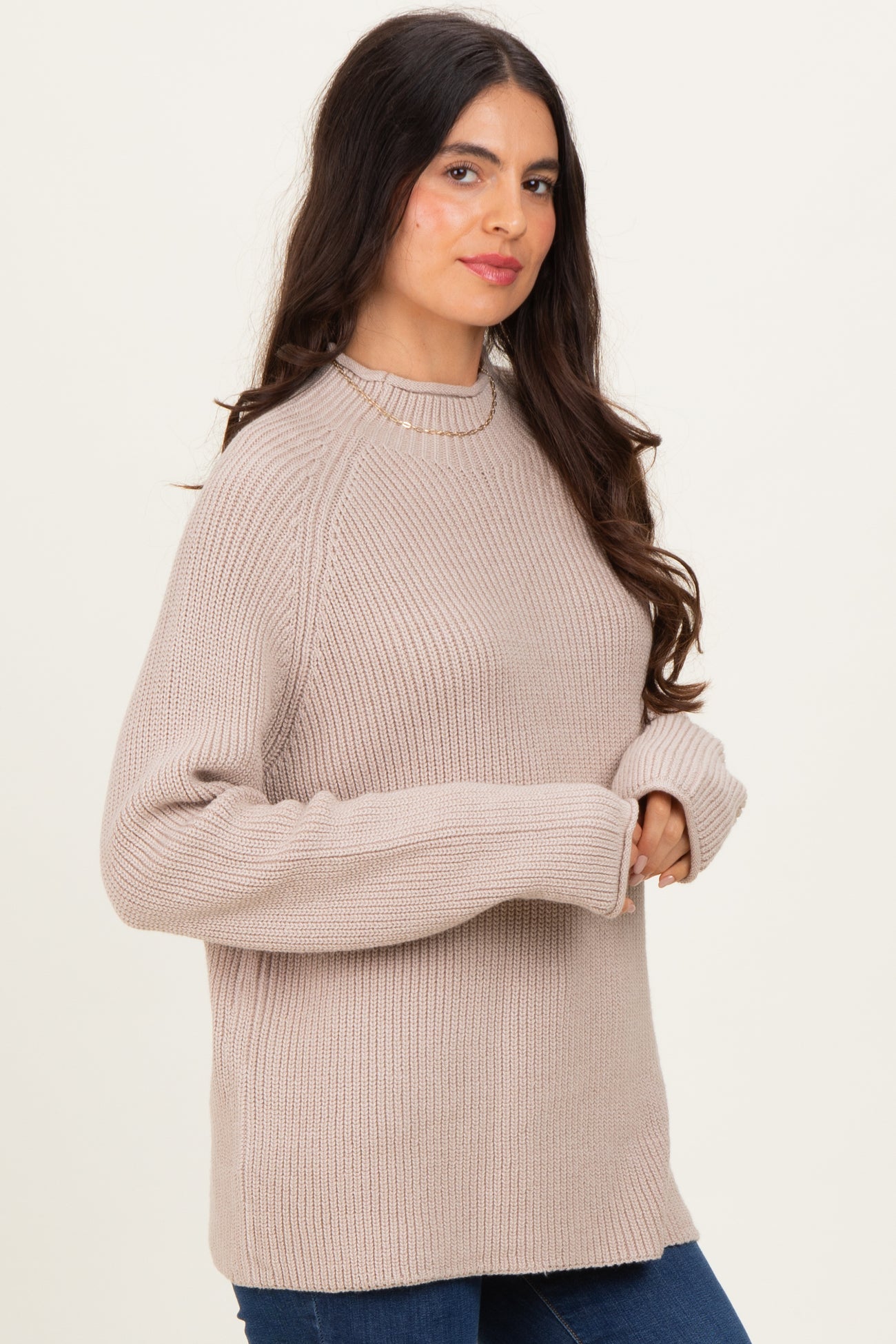 woman wearing a light beige oversized knit sweater with a crew neckline and ribbed texture