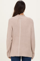 woman wearing a beige ribbed knit sweater, showing the back view and relaxed fit, paired with blue jeans