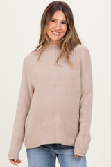 woman wearing a beige ribbed maternity sweater with long sleeves and a relaxed fit, showcasing her baby bump