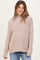 woman wearing a beige ribbed maternity sweater with long sleeves and a relaxed fit, showcasing her baby bump