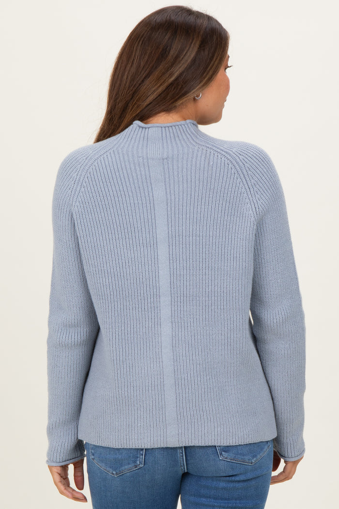 woman wearing a light blue maternity sweater with ribbed texture and fitted sleeves, seen from the back