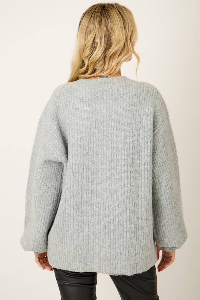woman wearing a cozy light grey oversized knit sweater viewed from the back