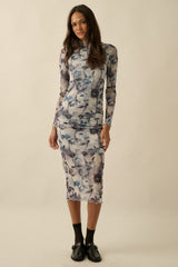 woman wearing a sheer floral long sleeve dress with a fitted silhouette and scalloped hem