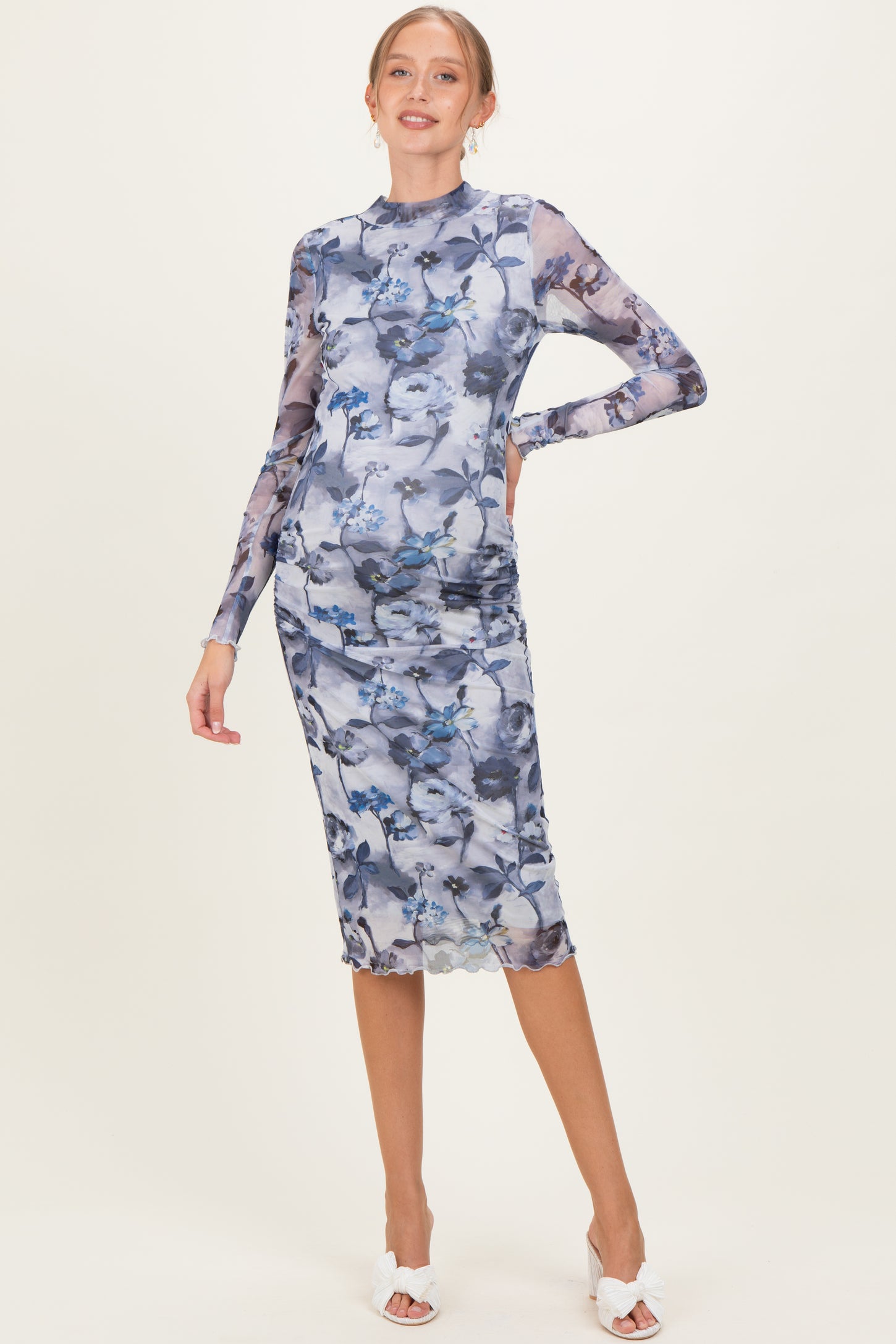 woman wearing a floral print long sleeve maternity dress with a fitted silhouette and visible baby bump