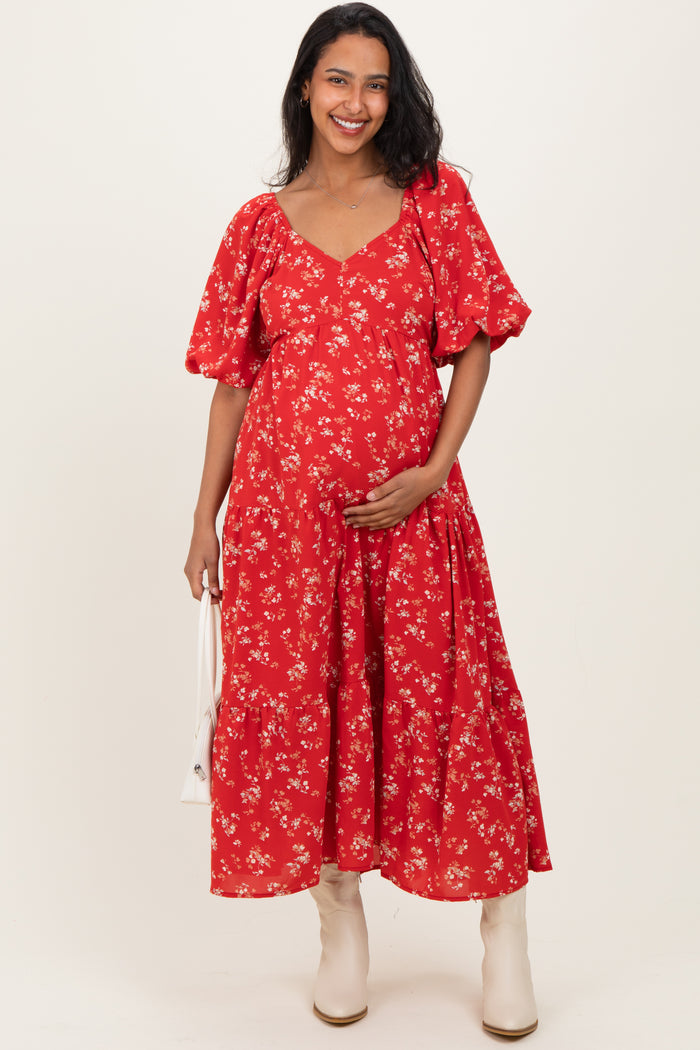 woman wearing a red floral maternity dress with puff sleeves and holding her baby bump
