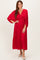 woman wearing a red pleated midi dress with long sleeves and a deep v-neckline