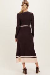 woman wearing a dark brown ribbed maternity dress with a cream stripe at the hem and a fitted silhouette, showing her baby bump