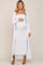 woman wearing a white ribbed maternity dress with a matching long cardigan and holding her baby bump