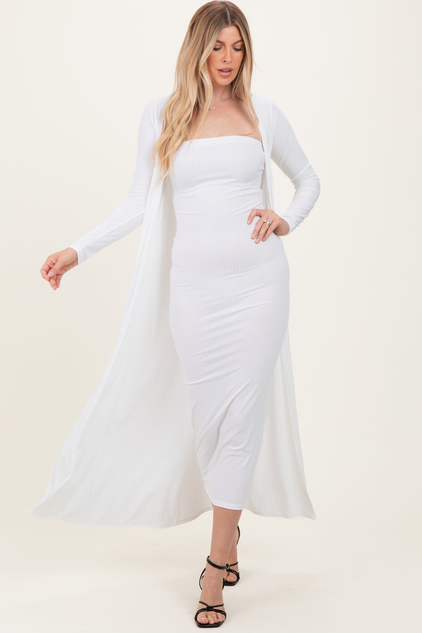 woman wearing a white ribbed midi dress with a long cardigan and strappy black heels