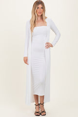 woman wearing a white ribbed maxi dress with a long cardigan and strappy black heels