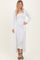 woman wearing a white ribbed maxi dress with a long cardigan and strappy black heels