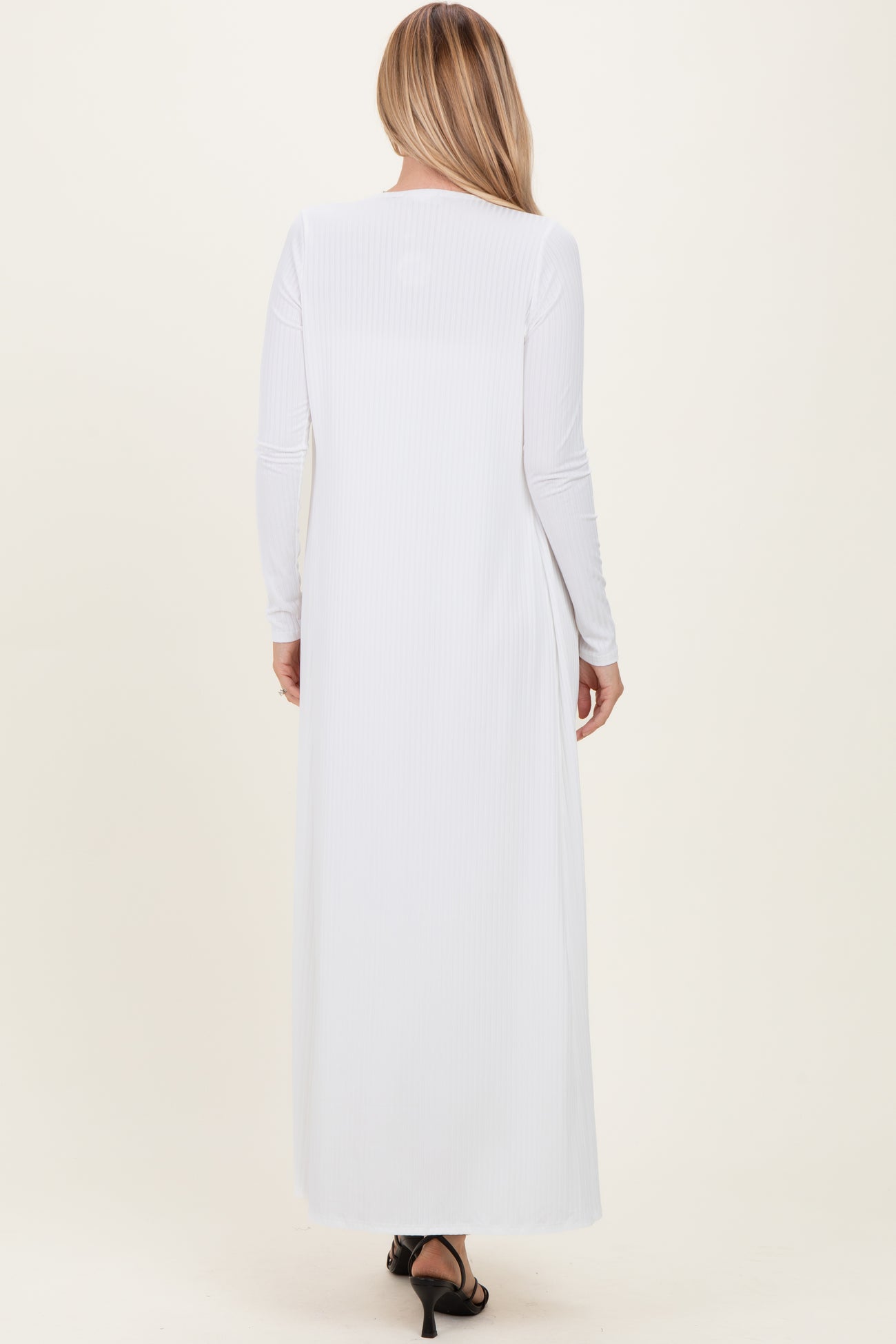 woman wearing a long white ribbed maxi dress with long sleeves, shown from the back