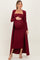 woman wearing a burgundy maternity ribbed dress with a long cardigan and holding her baby bump