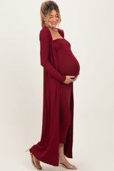 woman wearing a burgundy ribbed maternity set with a long cardigan and a fitted dress, showing her baby bump