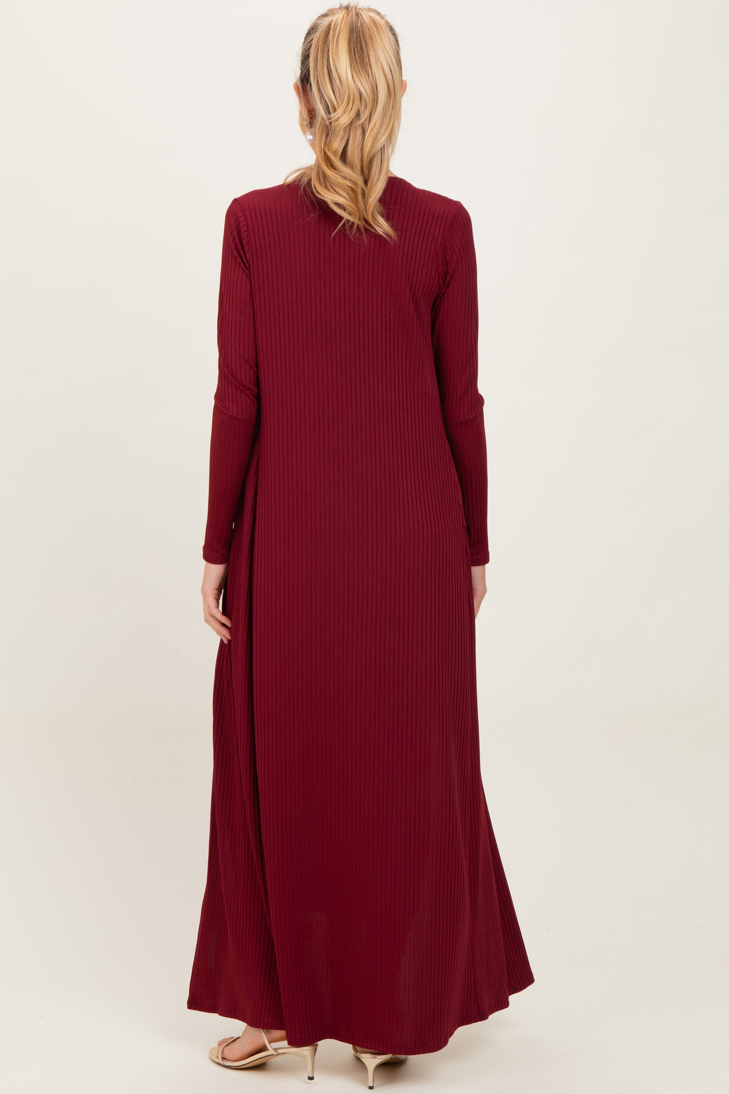 woman wearing a burgundy long sleeve maternity maxi dress, showing the back view and flowing style