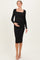 woman wearing a black long sleeve maternity dress with a square neckline and holding her baby bump