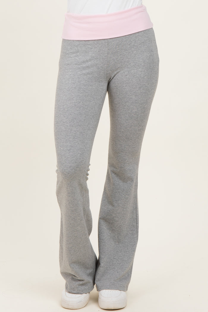 woman wearing gray flared sweatpants with a light pink waistband and white sneakers