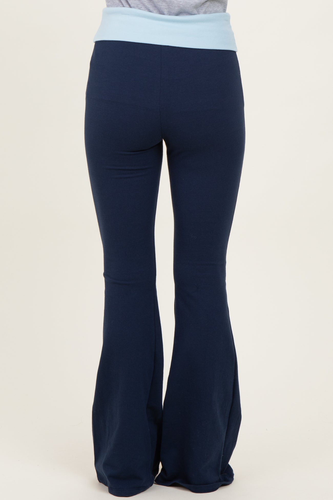 woman wearing navy blue flared yoga pants with a light blue waistband, viewed from the back