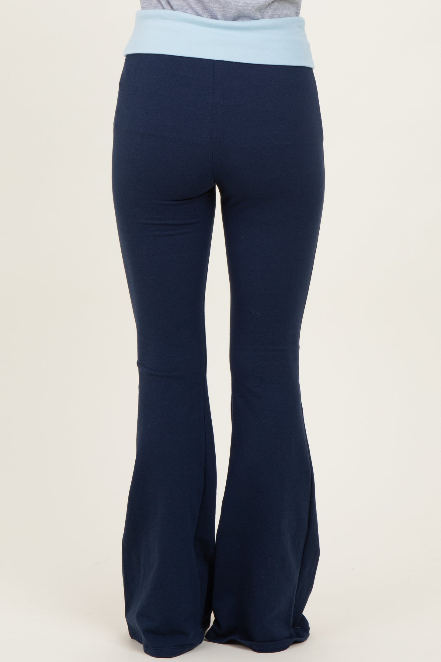 woman wearing navy blue flared yoga pants with a light blue waistband, viewed from the back