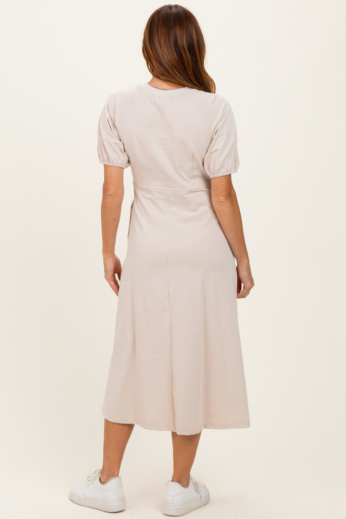 woman wearing a light beige midi dress with puff sleeves, shown from the back, paired with white sneakers