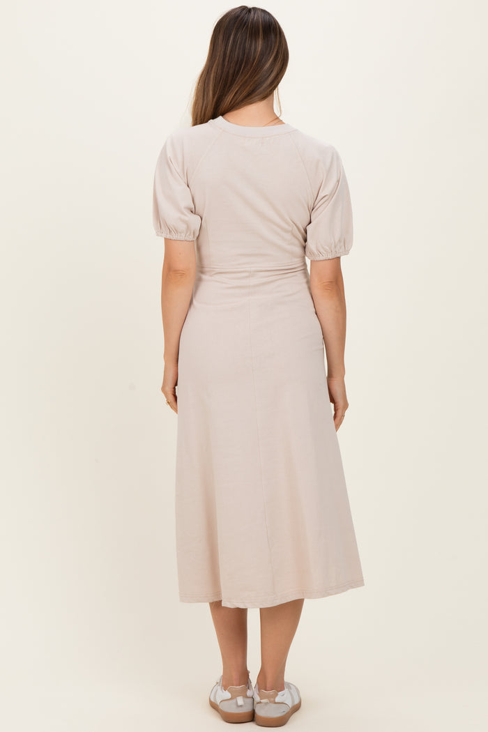 woman wearing a light beige puff sleeve maternity dress, view from the back, with a flowy midi length