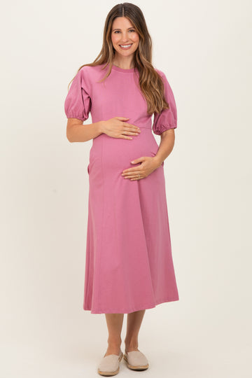 woman wearing a pink short sleeve maternity dress and holding her baby bump