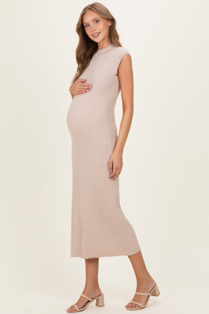 woman wearing a beige ribbed maternity dress and holding her baby bump