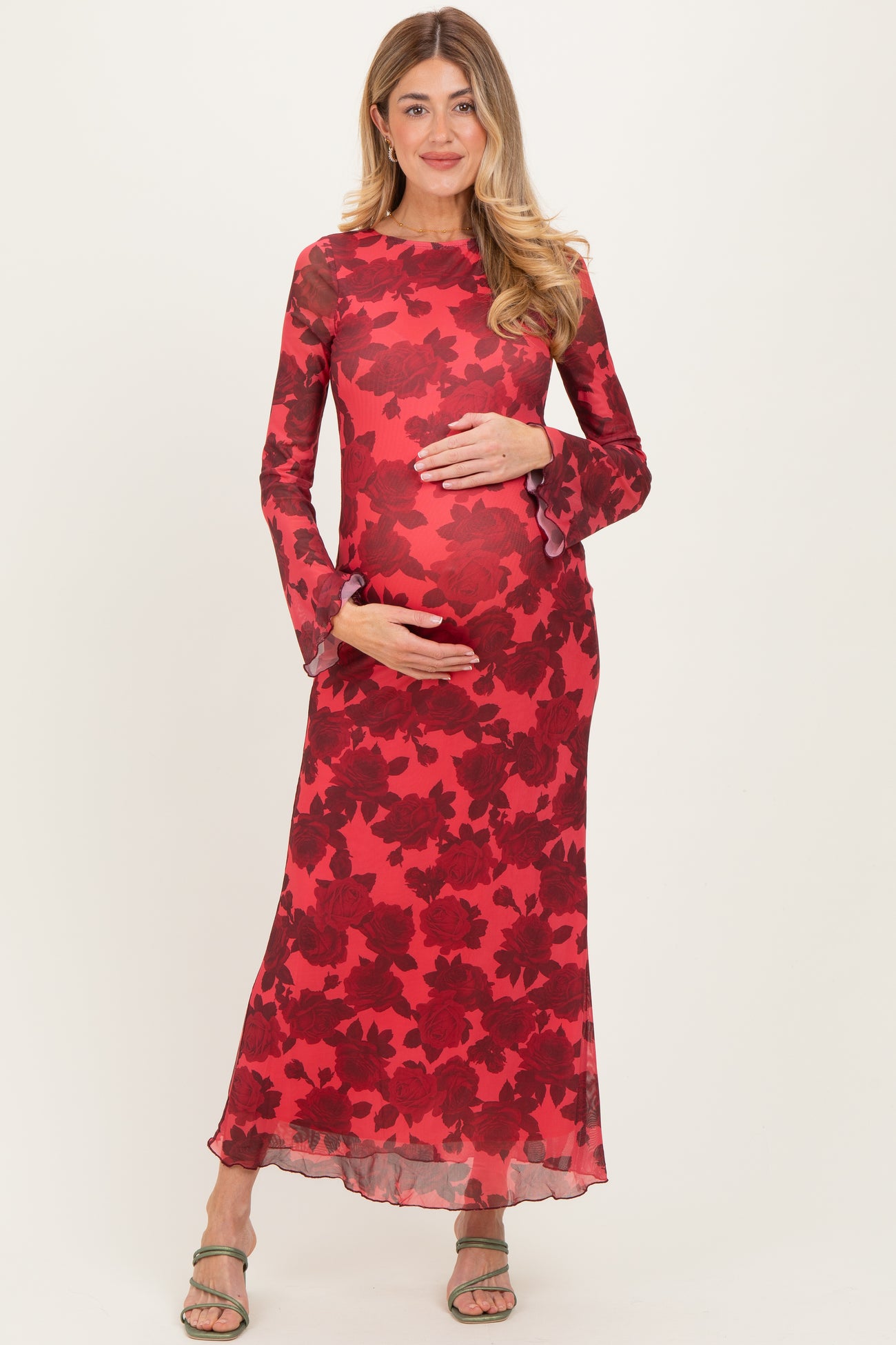 woman wearing a red floral long sleeve maternity dress and holding her baby bump
