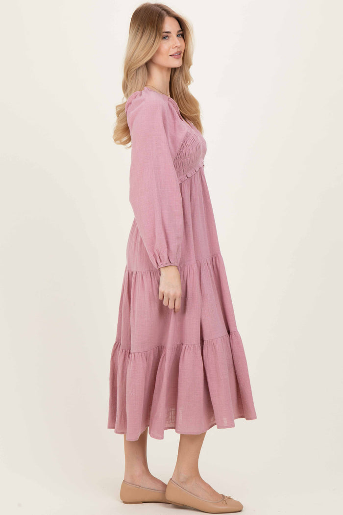 woman wearing a pink tiered maxi dress with long sleeves and smocked bodice
