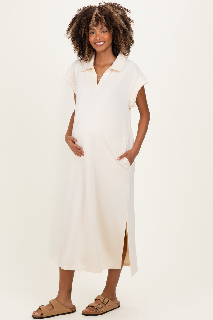 woman wearing a light peach maternity dress with short sleeves, side slits, and pockets, highlighting her baby bump