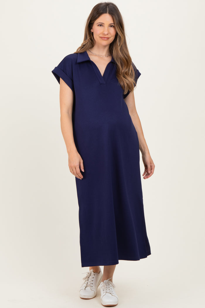 woman wearing a navy blue short sleeve maternity dress with a collared neckline and relaxed fit, showing baby bump