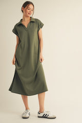 woman wearing an olive green short sleeve polo dress with a relaxed fit and side slit, paired with white sneakers