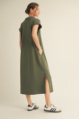 woman wearing an olive green midi polo dress with rolled sleeves and side slits, paired with white sneakers