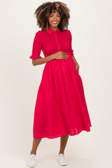 woman wearing a bright pink short sleeve maternity dress with buttons and holding her baby bump