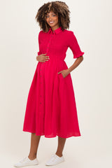 woman wearing a bright pink maternity dress with short sleeves, button front, and pockets, showing her baby bump