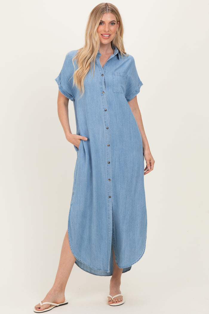 woman wearing a light blue denim shirt dress with short sleeves and pockets, standing in a relaxed pose