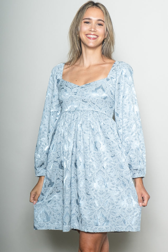 woman wearing a light blue lace long sleeve dress with a square neckline and a flared skirt