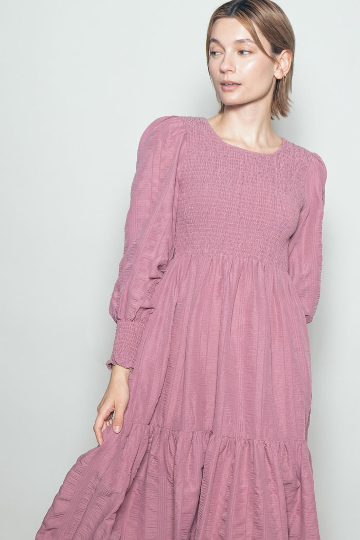 woman wearing a pink smocked long sleeve dress with ruffle hem and puff sleeves