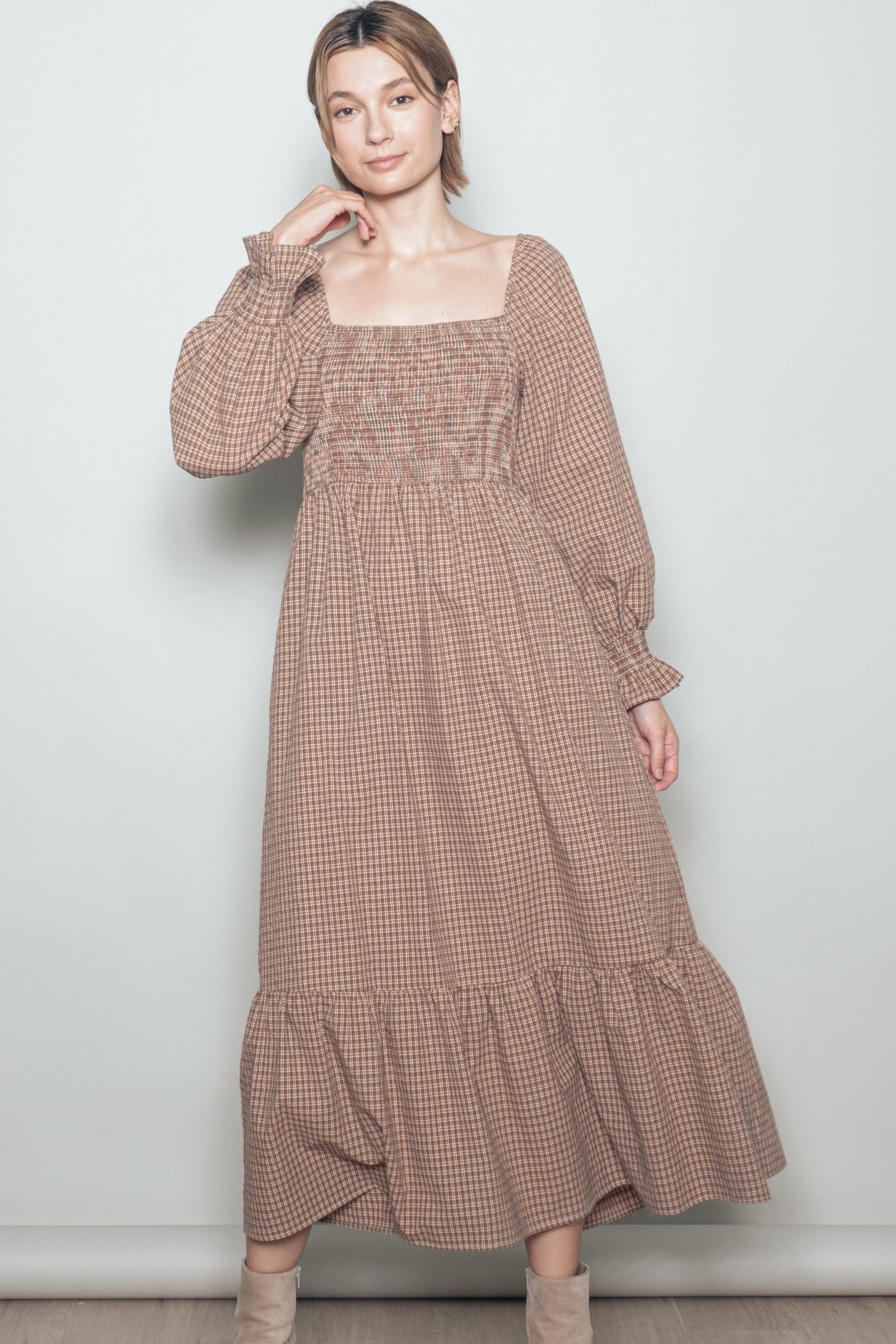 woman wearing a brown checkered long sleeve maxi dress with a square neckline and ruffled hem