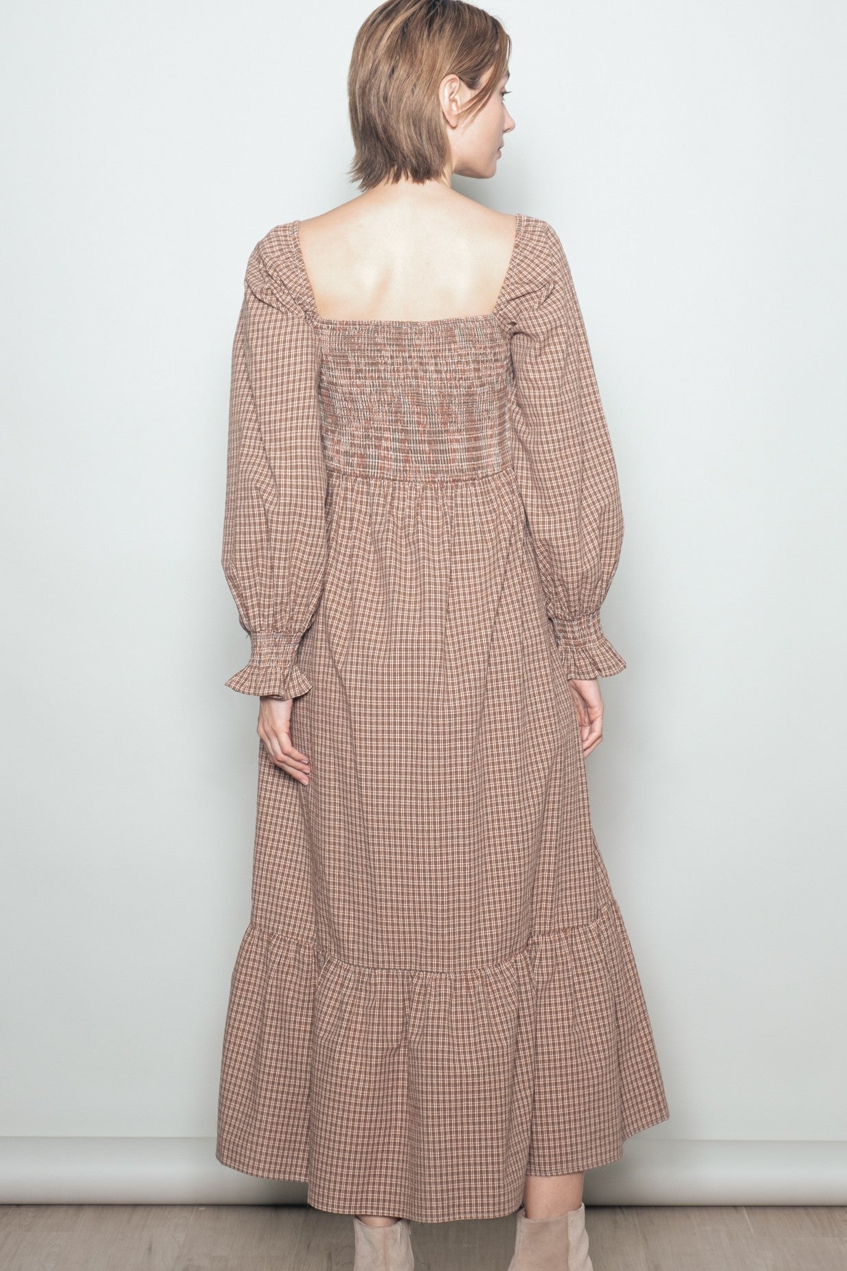woman wearing a brown checkered long sleeve maxi dress with a smocked back and ruffled hem