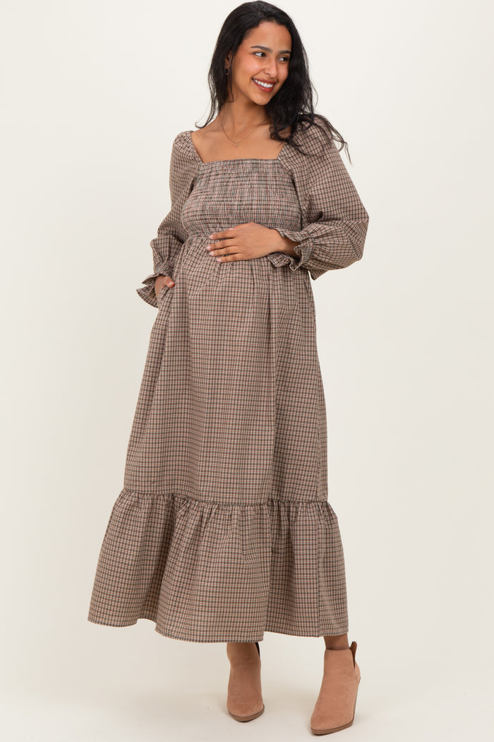 woman wearing a brown checkered maternity maxi dress with a square neckline, long sleeves, and a baby bump