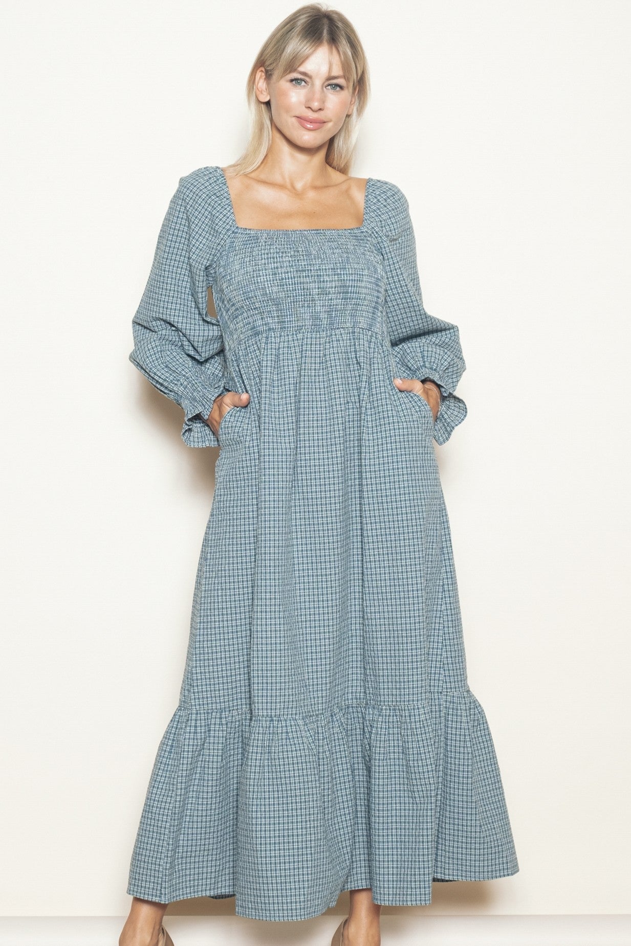 woman wearing a blue and white checkered long sleeve maxi dress with a square neckline and pockets