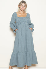 woman wearing a blue and white checkered long sleeve maxi dress with a square neckline and pockets
