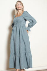 woman wearing a blue checkered long sleeve maxi dress with a smocked bodice and ruffle hem
