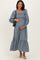 woman wearing a blue and white checkered maternity dress with puff sleeves and a tiered hem, holding her baby bump