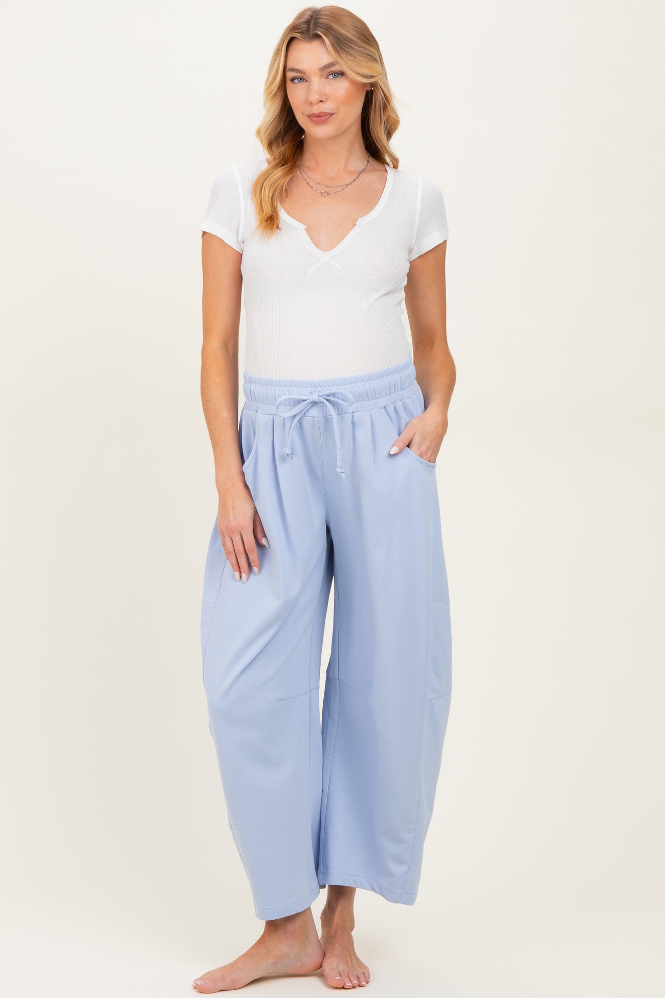 woman wearing a white short sleeve ribbed maternity top and light blue maternity wide leg pants with pockets