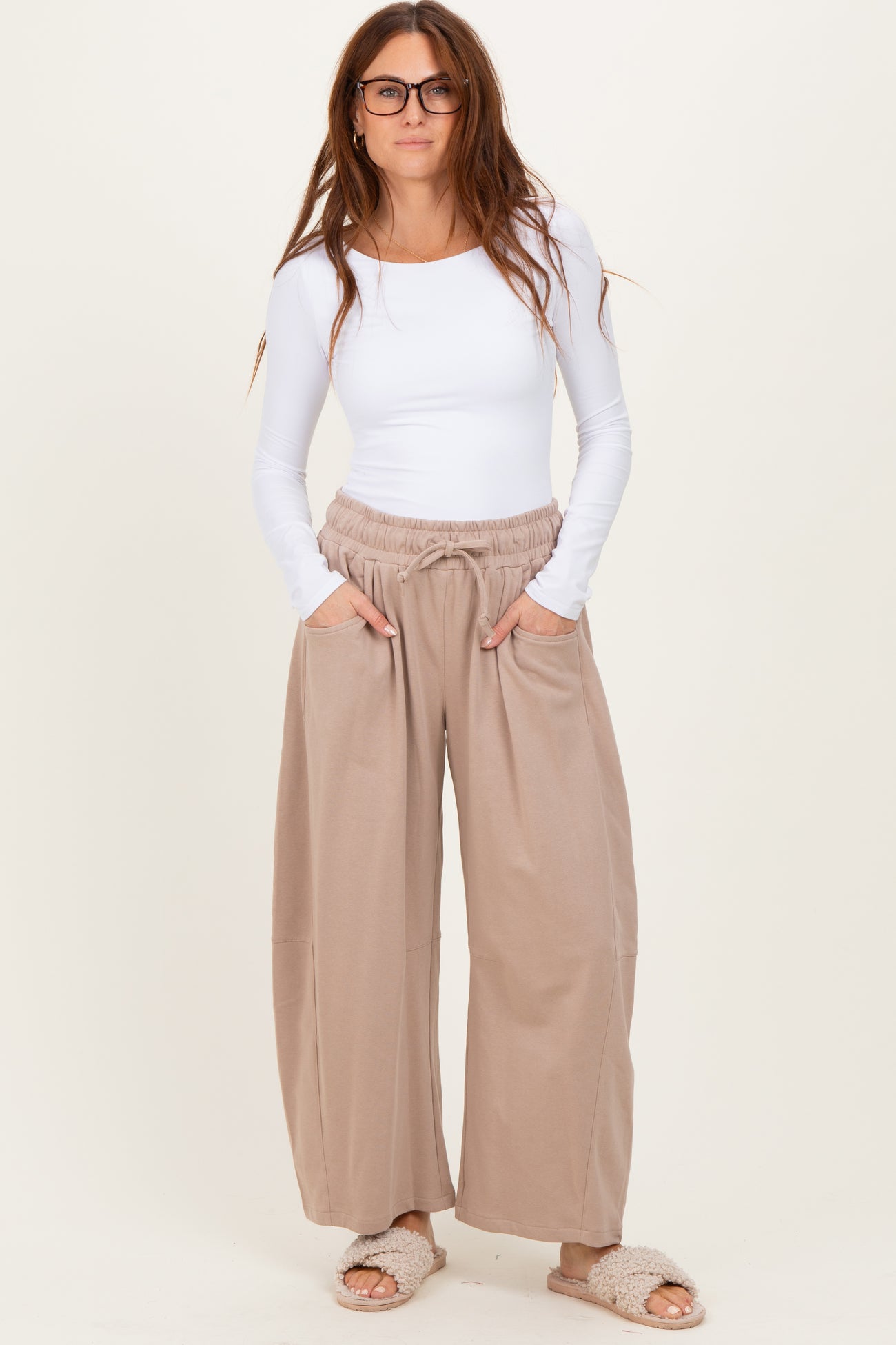 woman wearing a white long sleeve top and beige wide-leg pants with elastic waistband and pockets