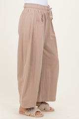 woman wearing beige wide-leg lounge pants with an elastic waistband and side pockets